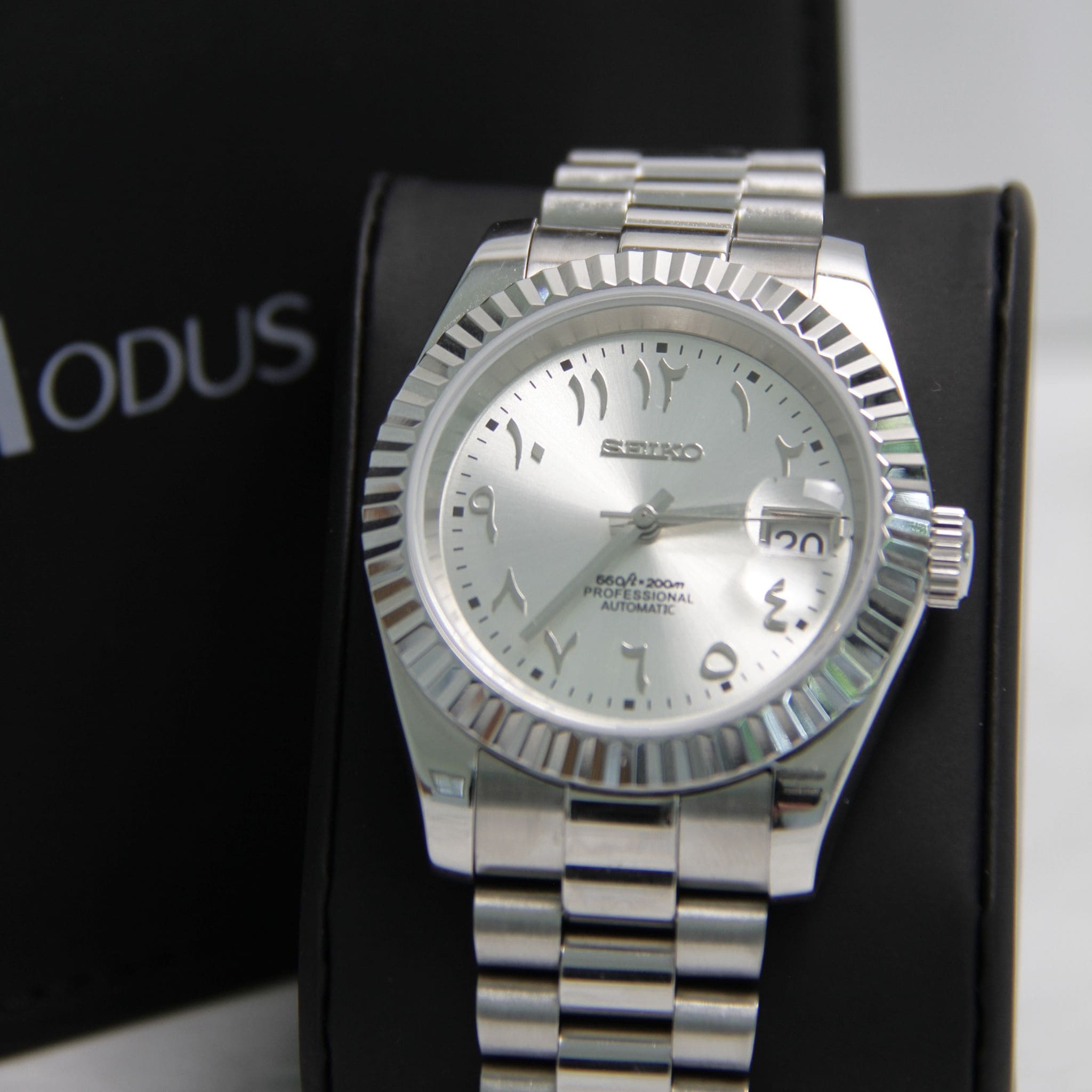 Montre Seiko mod datejust arabic gris argenté vu de face sur coussin