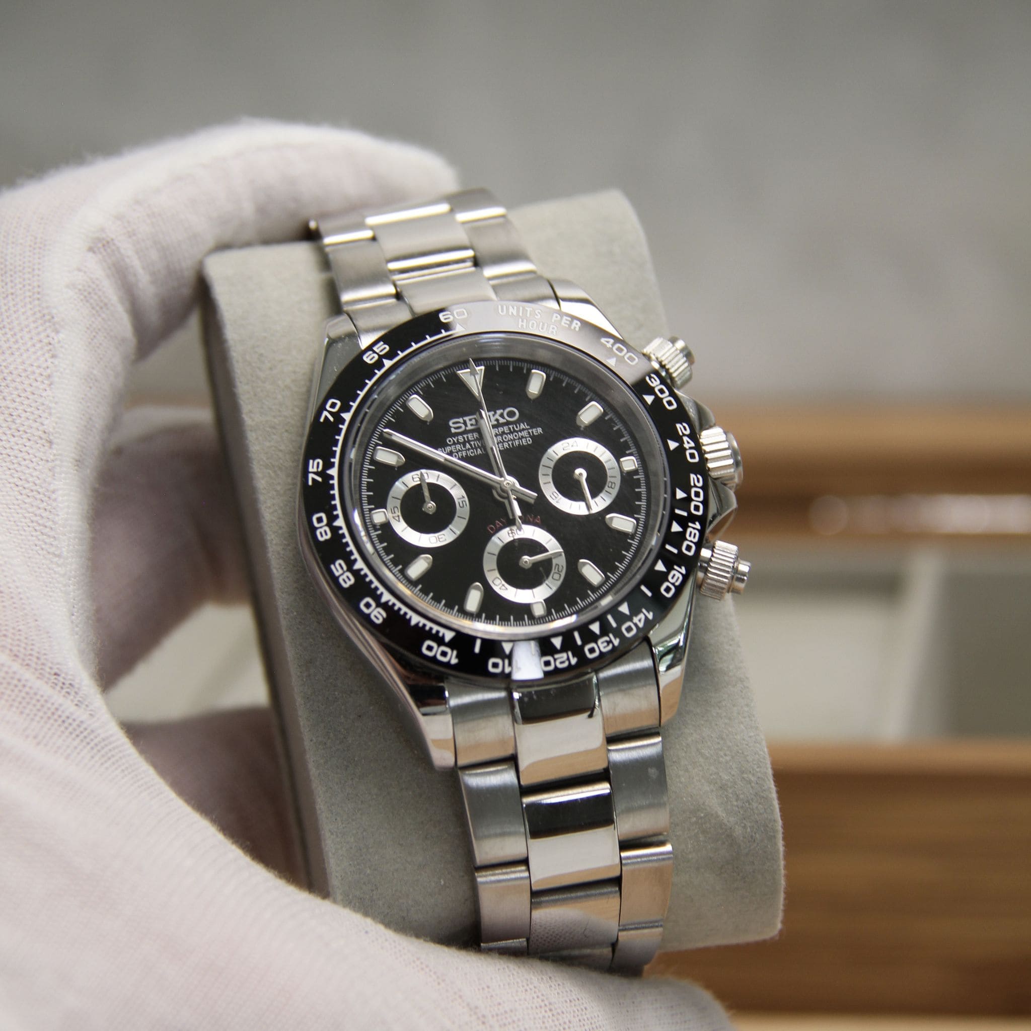 Montre Seiko mod daytona noir vu de face sur coussin.